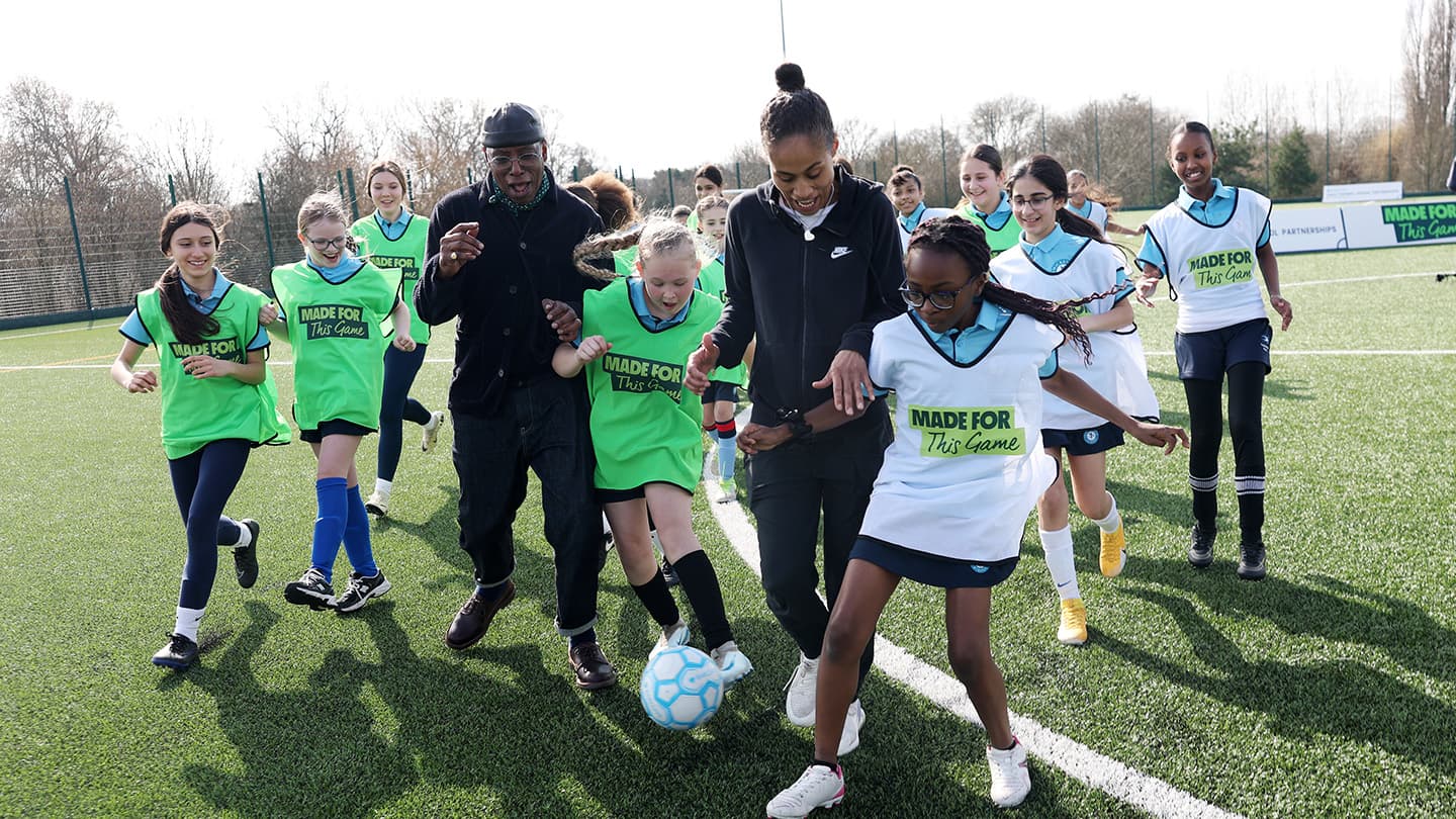 Ian Wright with young girls playing football, celebrating the growth of women's and girls' football in the UK